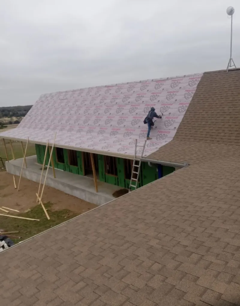 Worker preparing underlayment for a metal roof installation in West Melbourne